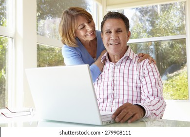 Senior Hispanic Couple In Home Office With Laptop