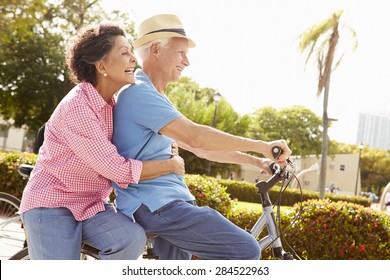 Senior Hispanic Couple Riding Bikes In Park