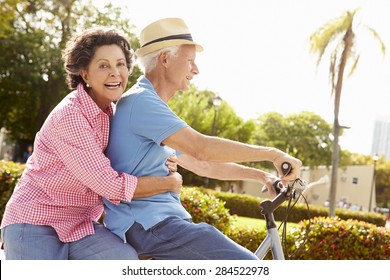 Senior Hispanic Couple Riding Bikes In Park