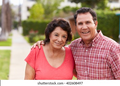 Senior Hispanic Couple Walking Along Sidewalk Together