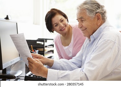 Senior Hispanic Couple Working On Computer At Home