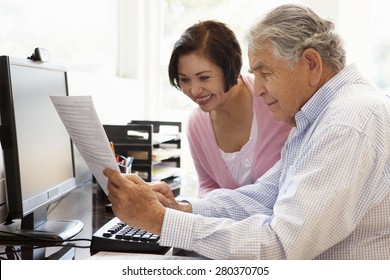 Senior Hispanic Couple Working On Computer At Home