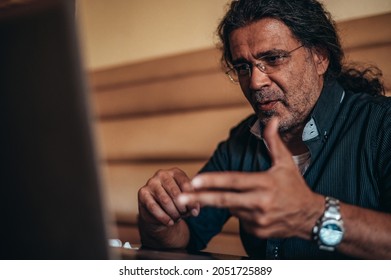 Senior hispanic cuban men using a laptop for an online video call while working in the cafe