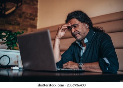 Senior hispanic cuban men using a laptop while having a headache from work stress