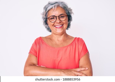 Senior hispanic grey- haired woman wearing casual clothes and glasses happy face smiling with crossed arms looking at the camera. positive person. 