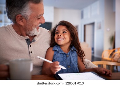 Senior Hispanic man with his granddaughter using tablet computer, looking at each other, close up - Powered by Shutterstock