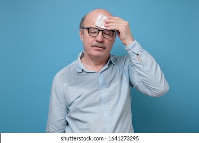 Senior Hispanic Man With Sweat Stain On His Shirt Suffering From Hot Weather. Studio Shot On Blue Wall. Problem With Hyperhidrosis