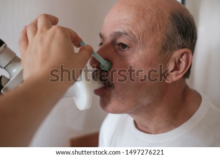 Senior hispanic man man testing breathing function by spirometry. Diagnosis of respiratory function in pulmonary disease
