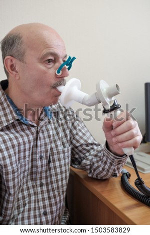 Senior hispanic man man testing breathing function by spirometry. Diagnosis of respiratory function in pulmonary disease