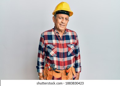 Senior Hispanic Man Wearing Handyman Uniform Relaxed With Serious Expression On Face. Simple And Natural Looking At The Camera. 