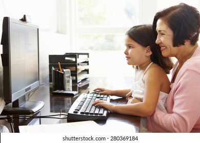 Senior Hispanic Woman With Computer And Grandchild