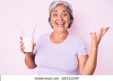 Senior Hispanic Woman Holding Glass Of Milk Celebrating Victory With Happy Smile And Winner Expression With Raised Hands 