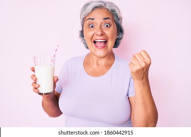 Senior Hispanic Woman Holding Glass Of Milk Screaming Proud, Celebrating Victory And Success Very Excited With Raised Arms 