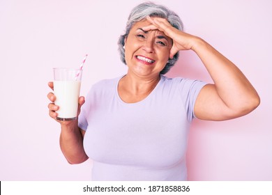 Senior Hispanic Woman Holding Glass Of Milk Stressed And Frustrated With Hand On Head, Surprised And Angry Face 