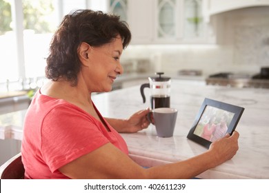 Senior Hispanic Woman At Home Looking At Old Photograph