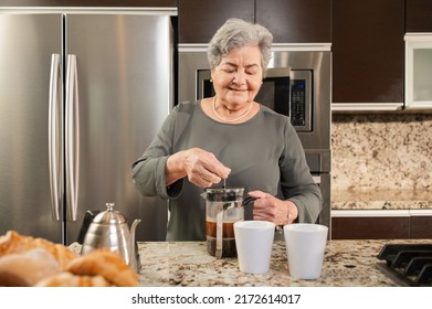 Senior Hispanic Woman Making Coffee In The Kitchen. Using A Pressure Method.
