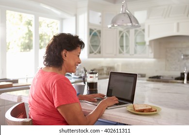 Senior Hispanic Woman Sitting At Home Using Laptop