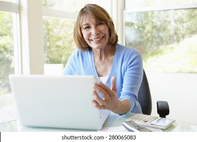 Senior Hispanic Woman Using Laptop In Home Office