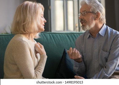 Senior husband and wife sit on couch at home talk dispute on family relations problem, stubborn mature couple having disagreement misunderstanding speak discuss health troubles or relationships - Powered by Shutterstock