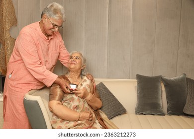 Senior Indian Couple Celebrating Anniversary, husband Giving Present jewellery gift - Powered by Shutterstock