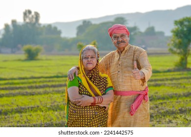 senior indian farmer couple showing thumps up at agriculture field