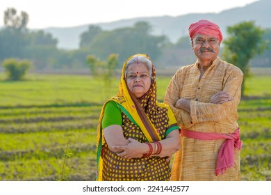 senior indian farmer couple standing at agriculture field.