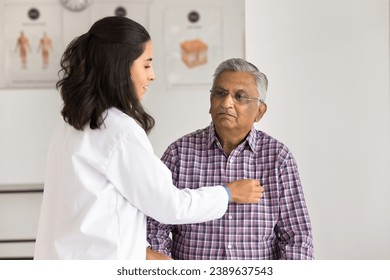 Senior Indian patient visiting medical practitioner woman for heart work checkup. Young Latin cardiologist doctor checking heartbeat rate of old man in clinic office, discussing health problems - Powered by Shutterstock