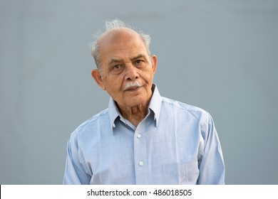 A Senior Indian / South Asian Man Against A Light Blue Background