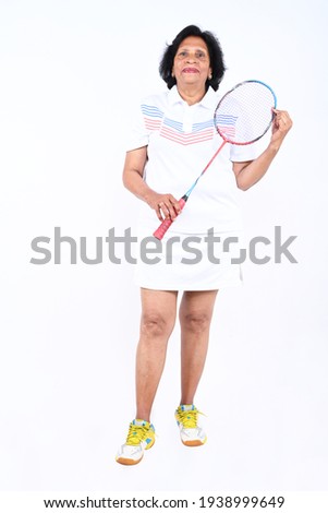 Senior Indian woman posing with badminton racket indoor