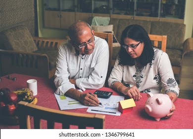 Senior Indian/asian Couple Accounting, Doing Home Finance And Checking Bills With Laptop, Calculator And Money While Sitting On Sofa/couch Or Dining Table At Home