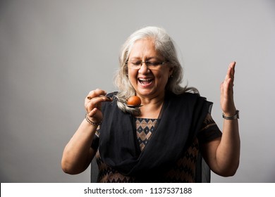 Senior Indian/asian Lady Eating Sweet Gulab Jamun With Spoon
