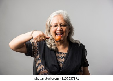 Senior Indian/asian Lady Eating Sweet Gulab Jamun With Spoon
