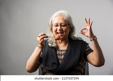 Senior Indian/asian Lady Eating Sweet Gulab Jamun With Spoon
