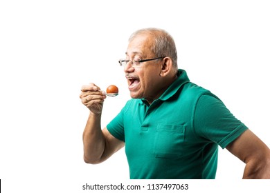 Senior Indian/asian Man Eating Sweet Gulab Jamun With Spoon