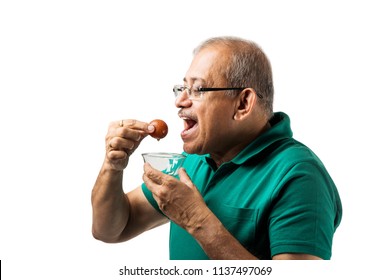 Senior Indian/asian Man Eating Sweet Gulab Jamun With Spoon