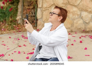 Senior Influencer Using Smart Phone To Take Pictures. Baby Boomer Woman Travels, Making Video Vlog And Using Mobile Phone.