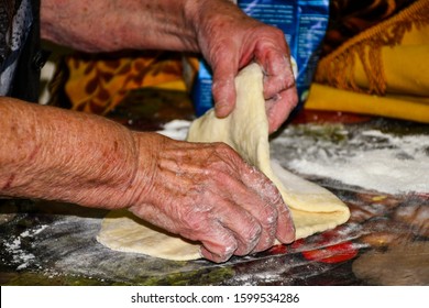 Senior  italian woman hands knead dough on a table in her home kitchen. Grandma making pasta the old traditional way in her home - Powered by Shutterstock