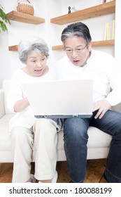 Senior Japanese Couple Being Surprised At Seeing A Laptop