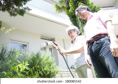 Senior Japanese Couple Watering Plants In The Garden