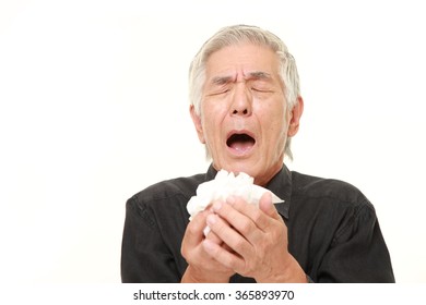 senior Japanese man with an allergy sneezing into tissue - Powered by Shutterstock