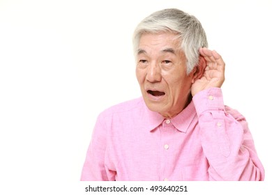 Senior Japanese Man With Hand Behind Ear Listening Closely