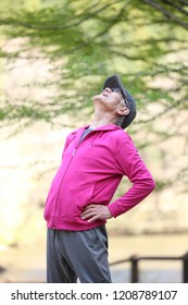 Senior Japanese Man In Pink Wear Doing Physical Exercise Standing Back Bend Outdoor