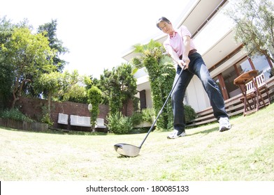 Senior Japanese man practicing golf in the backyard