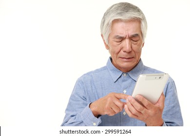Senior Japanese Man Using Tablet Computer Looking Confused