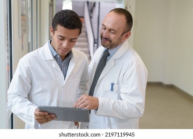 senior and junior doctors looking at tablet pc - Shutterstock ID 2197119945