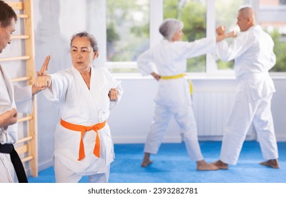 Senior karate practitioner engage in fierce fight, perseverance during martial arts discipline, middle-aged teacher and mature followers. Work on yourself, increase endurance, determination, courage - Powered by Shutterstock