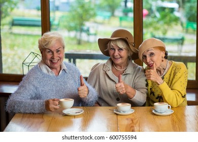 Senior ladies showing thumbs up. Three women and coffee cups. Everything is great.