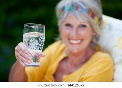 Senior Lady Drinking Sparkling Water In Summer