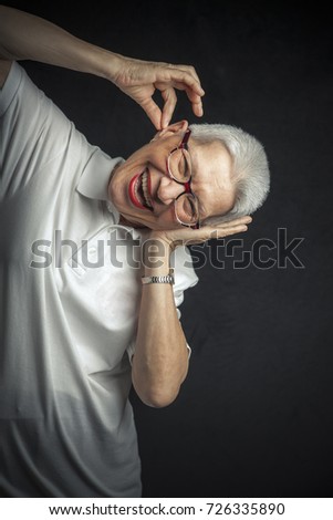 Senior lady pulling a prank, playing childish, putting some fake drops in her ear