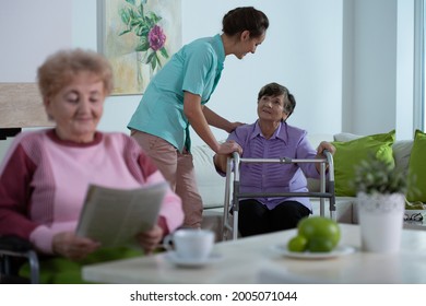 Senior Lady Reading A Newspaper In Common Room Of Professional Nursing Home